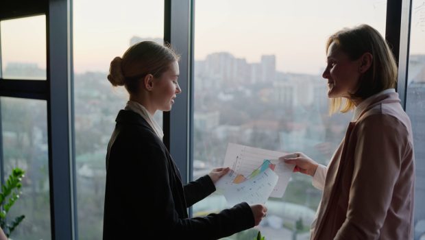 confident-young-blonde-girl-in-a-business-uniform-shows-her-papers-and-research-on-the-SBI-350596436